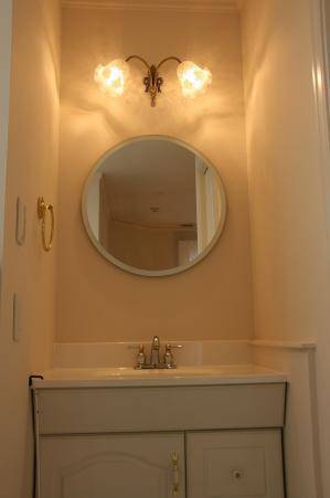 アンティーク調でリボンのデザインのブラケットライトを洗面所の照明として鏡の上に設置