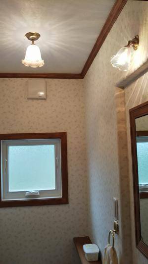 少し大きなトイレに、おしゃれな天井灯と鏡の上のブラケットライトを