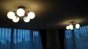 広々としたリビングルームの天井に設置したおしゃれなアンティーク風照明―白いガラスと真鍮製灯具の組み合わせが美しい