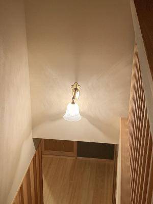 2階から階段を見下ろした光景。装飾美あるおしゃれなブラケットライトが階段を優しく照らしています