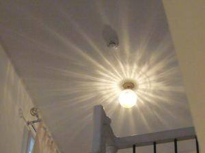 階段を上った先の廊下に、光の模様が美しい天井灯が見えています