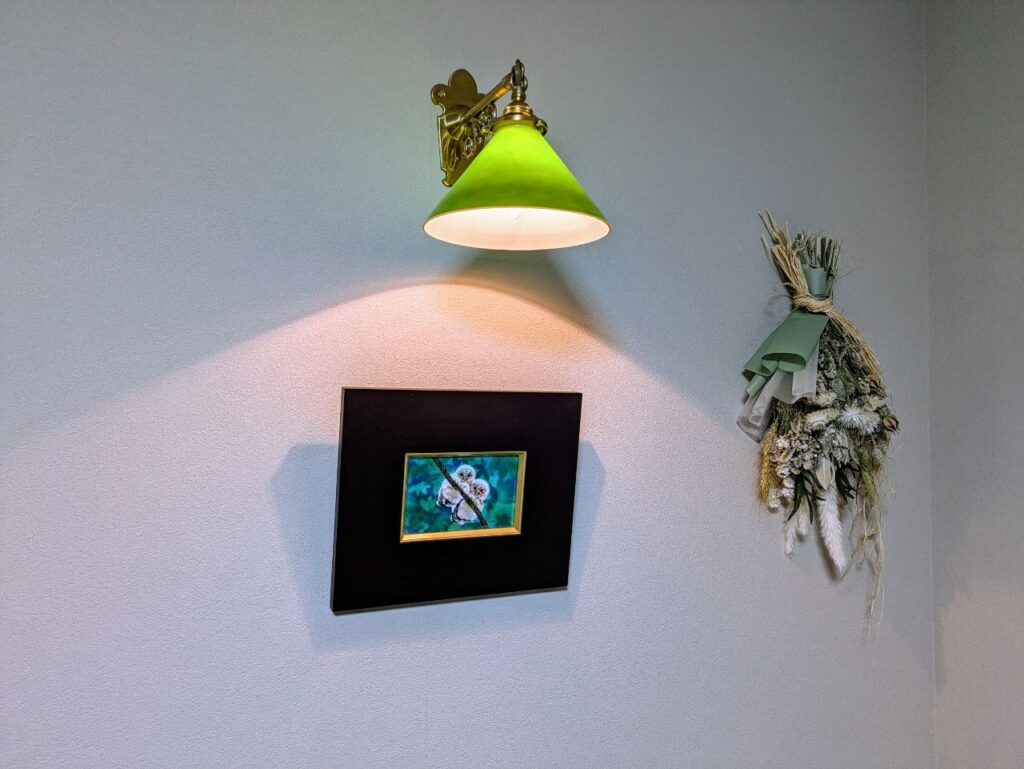 壁の絵画をおしゃれに照らしてくれるブラケットライト お部屋のグリーンにあわせてシェードもセレクト　I40邸